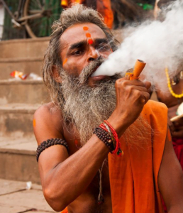 sadhu fumando de la pipa a las orillas del ganges en varanasi, Benares, India