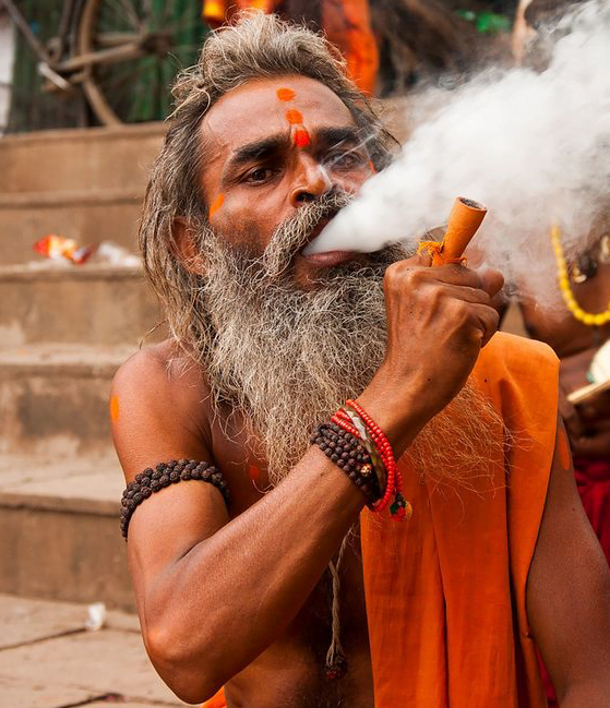 sadhu fumando de la pipa a las orillas del ganges en varanasi, Benares, India